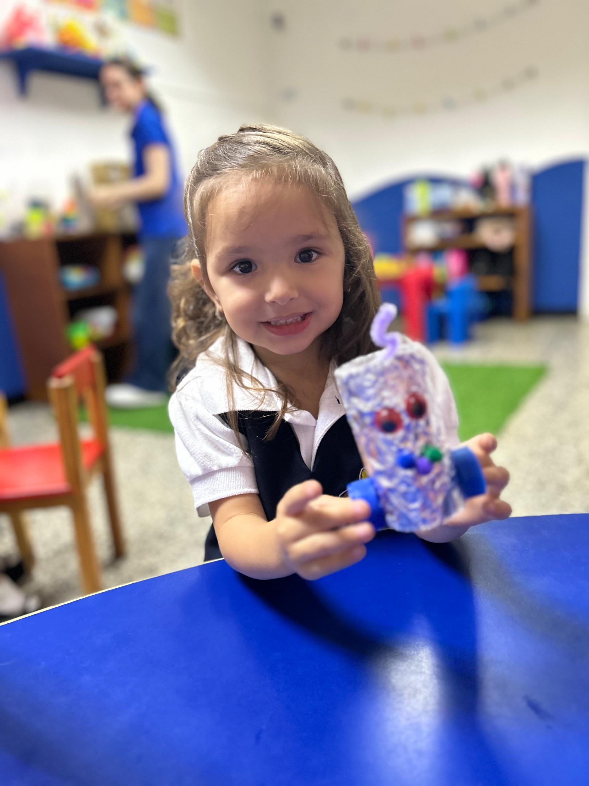 Niña mostrando una manualidad hecha con material reciclado