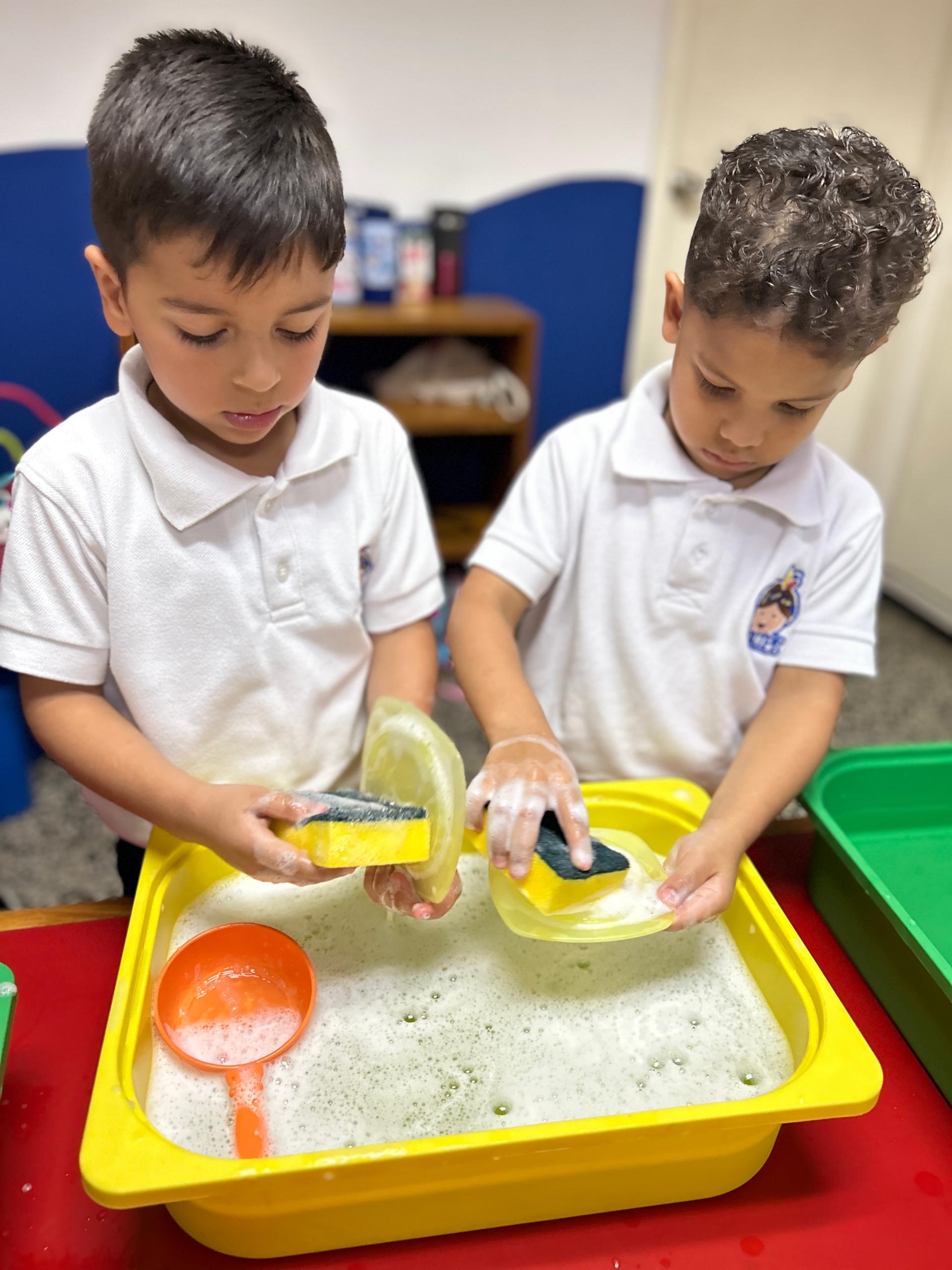 Niños aprendiendo hábitos de higiene lavando trastes